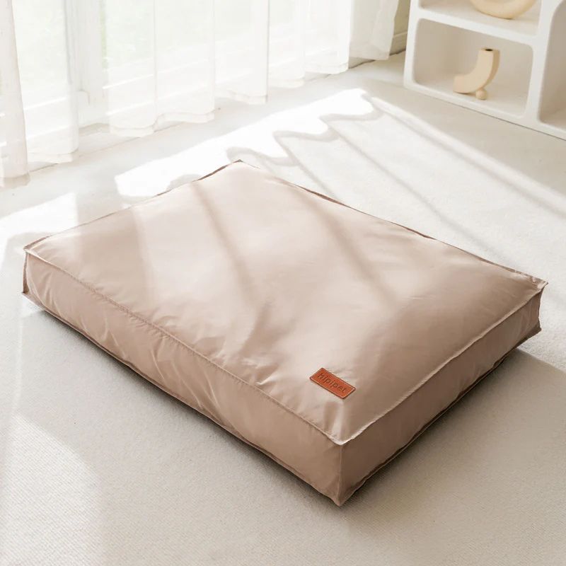 Beige pet bed on a white floor with a neutral background