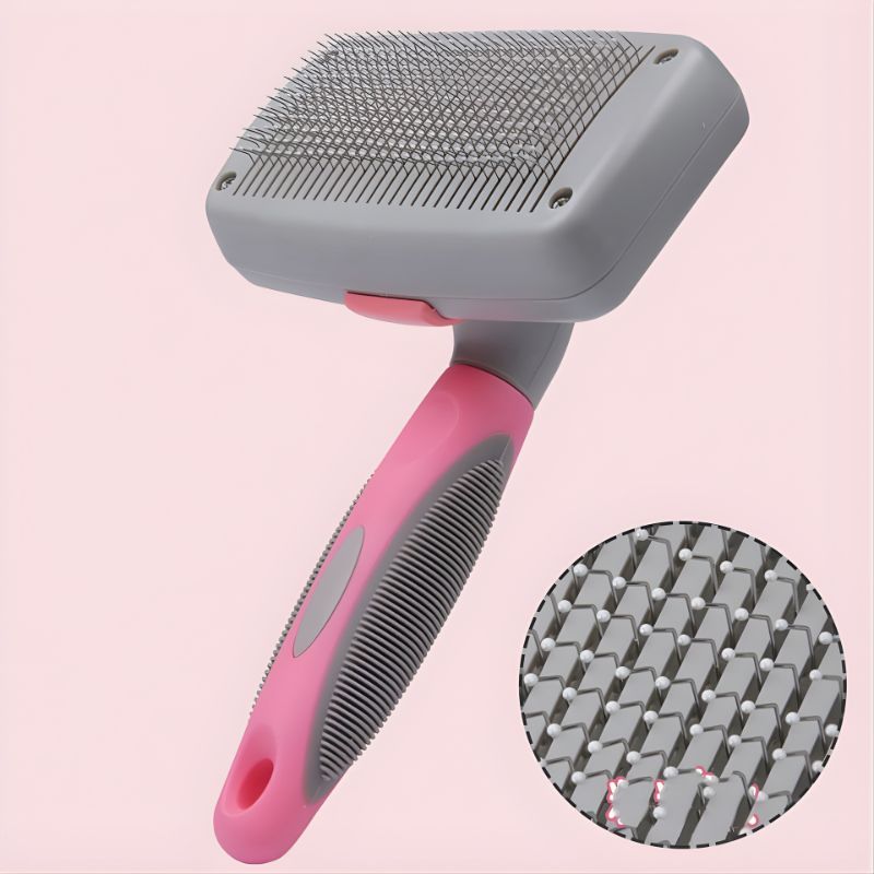 Pet grooming brush with pink handle and gray bristles on a pink background